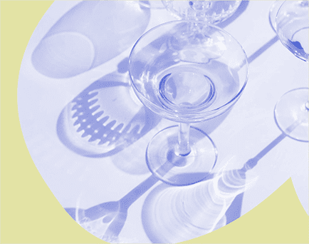 Grafika monochromatyczna w kolorze niebiesko-żółtym ze zdjęciem kieliszków do szampana rzucających cień na stół.