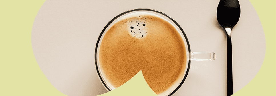 Zdjęcie filiżanki czarnej kawy z łyżeczką leżącą po prawej stronie oraz żółtym motywem graficznym na zdjęciu.
